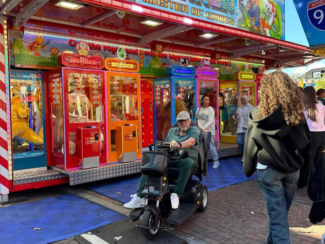 Man met scootmobiel rijdt over oprit op kermis